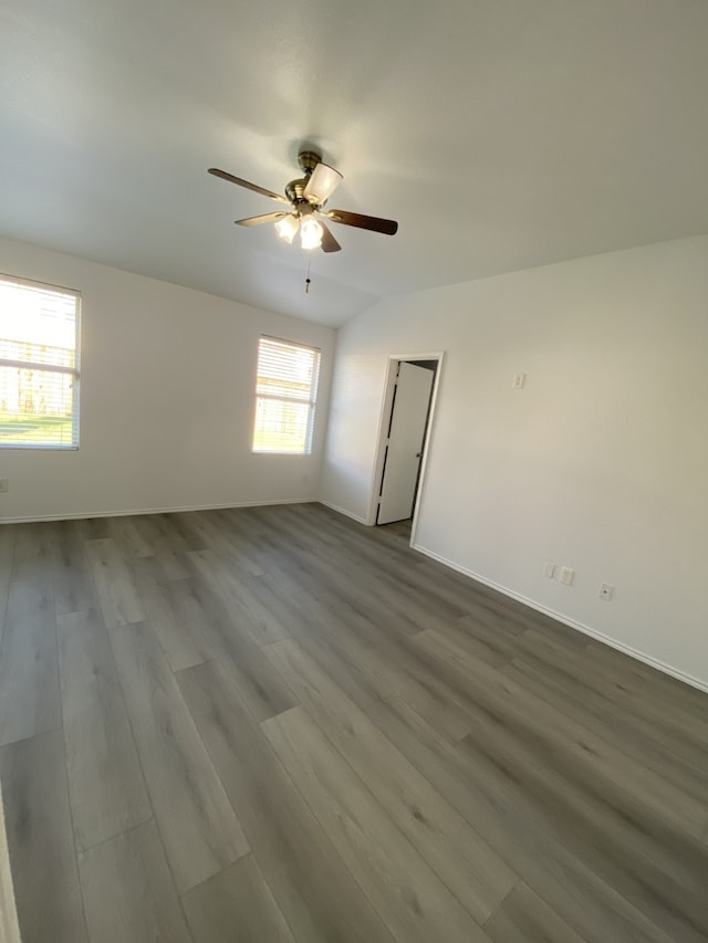 spare room featuring ceiling fan, dark wood-type flooring, and baseboards