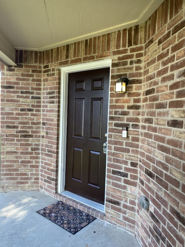 entrance to property featuring brick siding