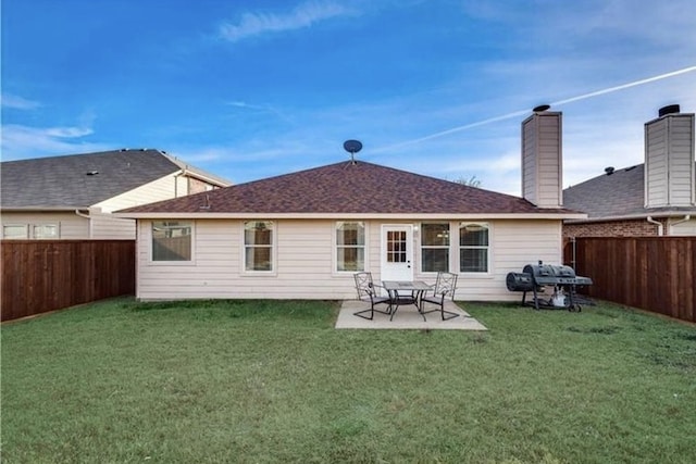 rear view of house featuring a patio area, a fenced backyard, a shingled roof, and a yard