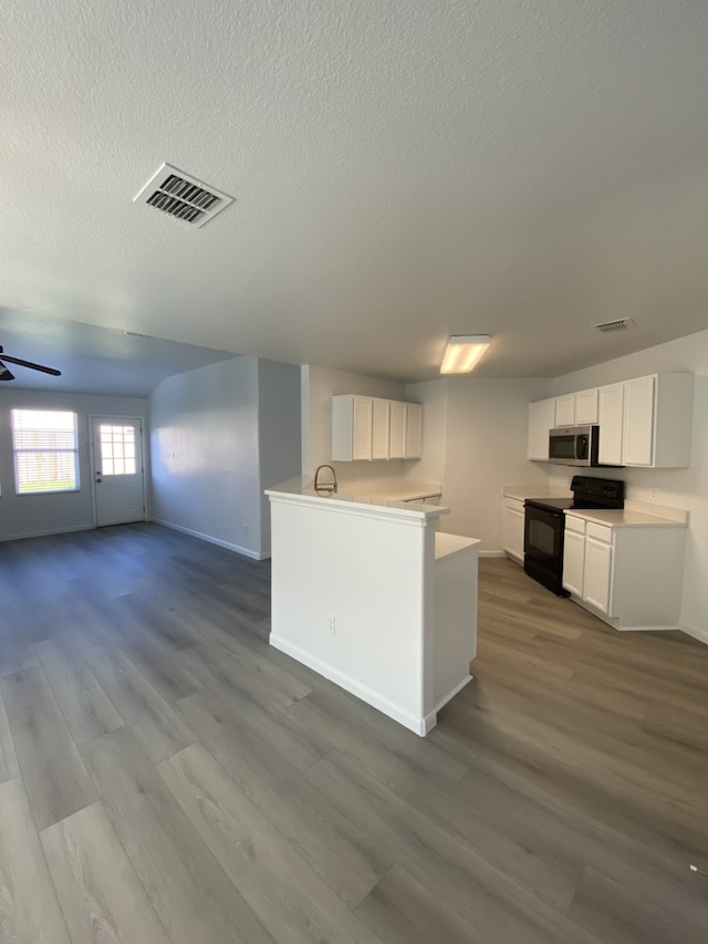 kitchen featuring black range with electric cooktop, visible vents, white cabinetry, stainless steel microwave, and dark wood finished floors