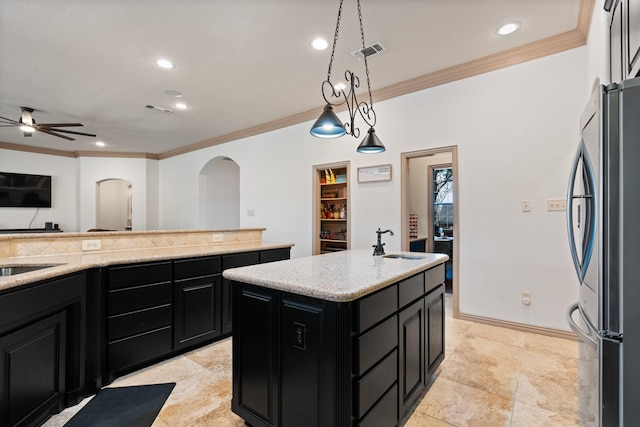 kitchen featuring dark cabinets, freestanding refrigerator, visible vents, and a sink