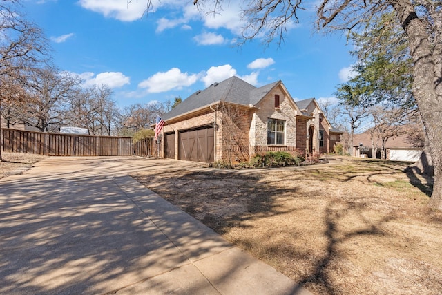 view of home's exterior with brick siding, concrete driveway, an attached garage, fence, and stone siding