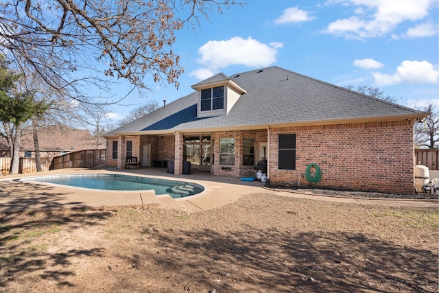 rear view of house featuring a fenced backyard, brick siding, a shingled roof, a fenced in pool, and a patio area