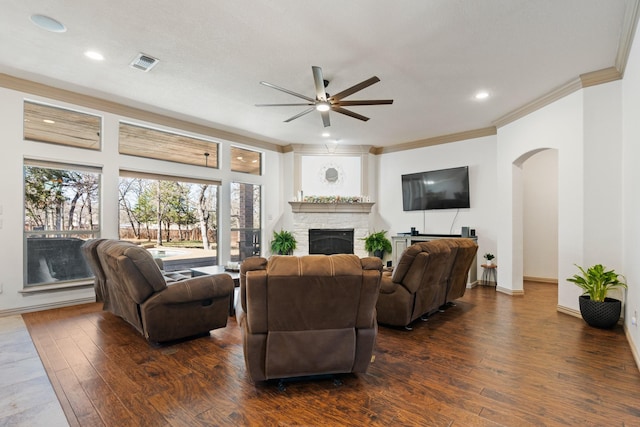 living area featuring arched walkways, dark wood-style flooring, visible vents, and a fireplace