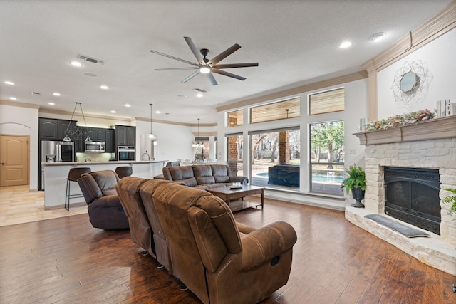 living room with hardwood / wood-style flooring, a fireplace, visible vents, and crown molding