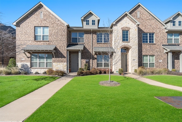 townhome / multi-family property featuring stone siding, brick siding, and a front yard