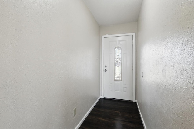 entryway with a textured wall, dark wood-type flooring, and baseboards