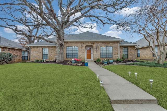 view of front facade with a shingled roof, a front lawn, and brick siding