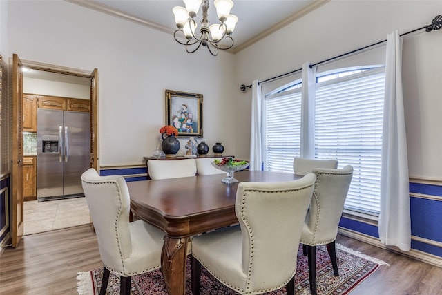 dining room featuring a notable chandelier, light wood-type flooring, and crown molding