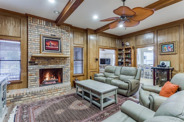 living area featuring wood walls, a fireplace, a ceiling fan, and beamed ceiling