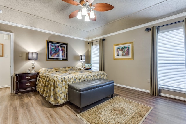 bedroom featuring ornamental molding, a textured ceiling, baseboards, and wood finished floors