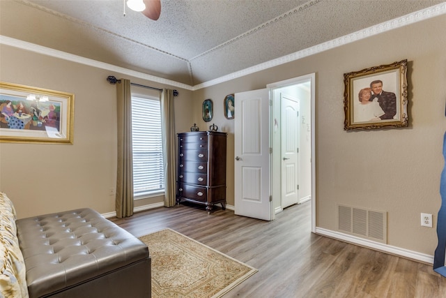 living area featuring lofted ceiling, wood finished floors, visible vents, and crown molding