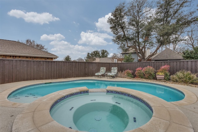 view of swimming pool with a fenced backyard and a pool with connected hot tub