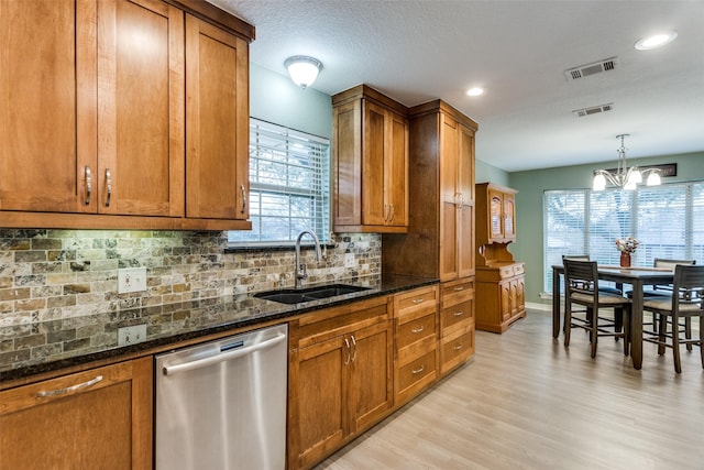 kitchen with a sink, visible vents, stainless steel dishwasher, dark stone counters, and brown cabinetry