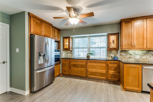 kitchen featuring stainless steel appliances, brown cabinetry, and dark stone countertops