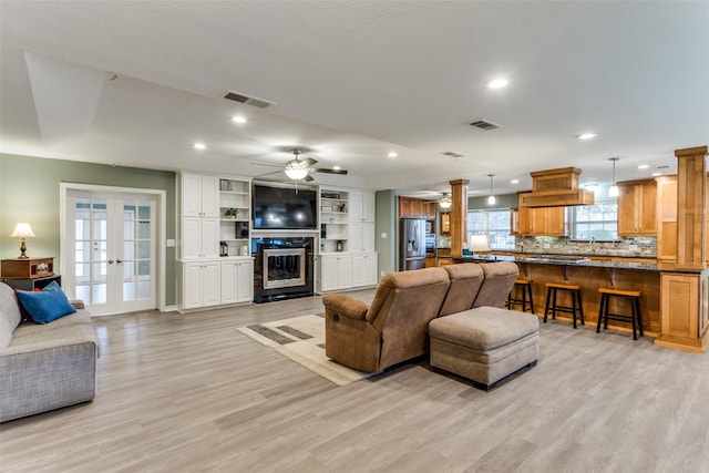 living area featuring visible vents, a glass covered fireplace, french doors, light wood-style floors, and recessed lighting