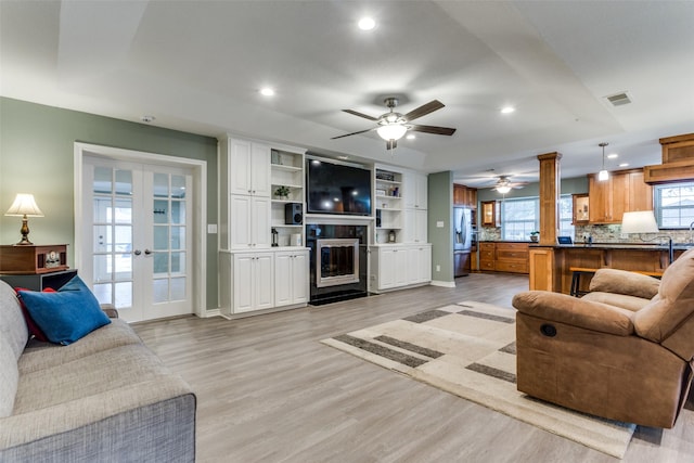 living room with visible vents, light wood-style flooring, a fireplace with flush hearth, french doors, and recessed lighting