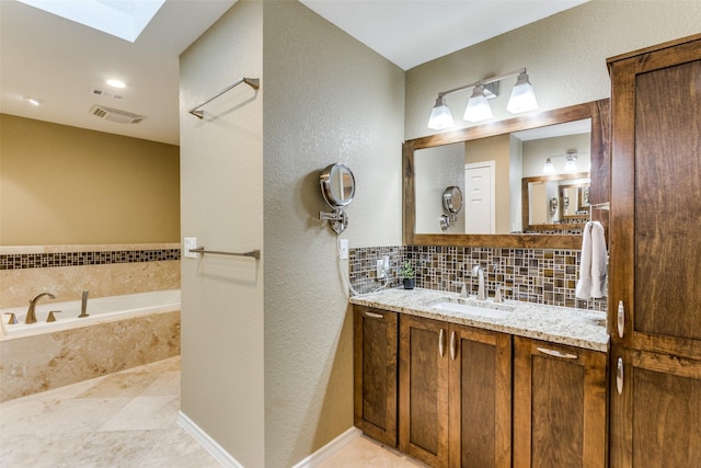 full bath with a skylight, vanity, visible vents, a bath, and decorative backsplash