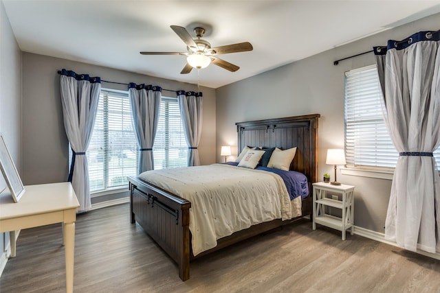 bedroom with ceiling fan, baseboards, and wood finished floors