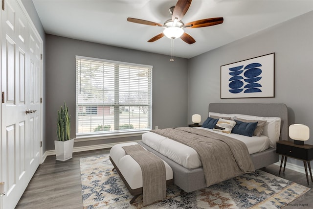 bedroom featuring wood finished floors, a ceiling fan, and baseboards