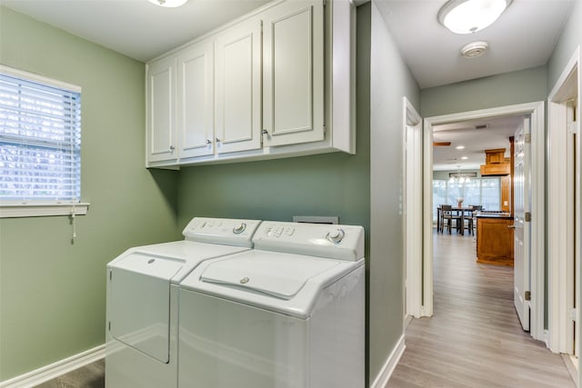 washroom featuring light wood-type flooring, cabinet space, baseboards, and washer and clothes dryer