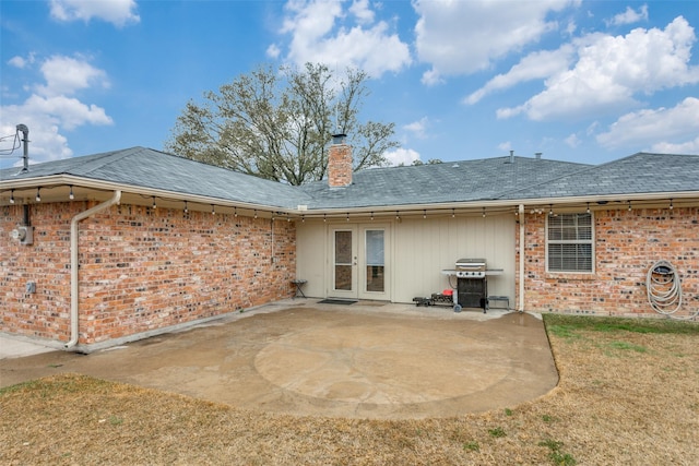 back of property featuring brick siding, a chimney, a patio, and french doors