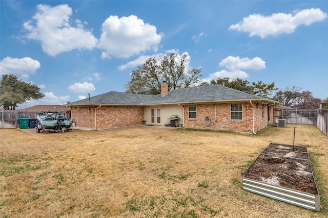 back of property featuring central air condition unit, brick siding, fence, a lawn, and a chimney