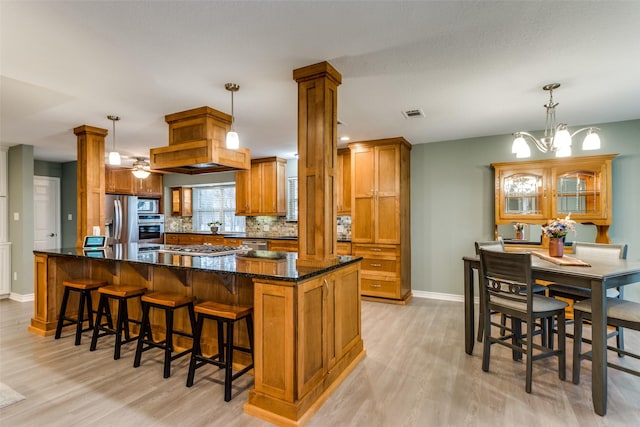 kitchen featuring brown cabinets, decorative columns, pendant lighting, and stainless steel appliances