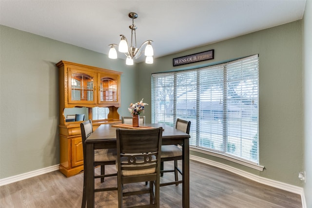 dining space featuring baseboards, light wood-style flooring, and a notable chandelier