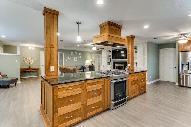 kitchen featuring open floor plan, appliances with stainless steel finishes, brown cabinets, decorative light fixtures, and ornate columns