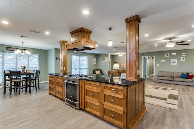 kitchen featuring stainless steel gas stove, ornate columns, pendant lighting, and open floor plan