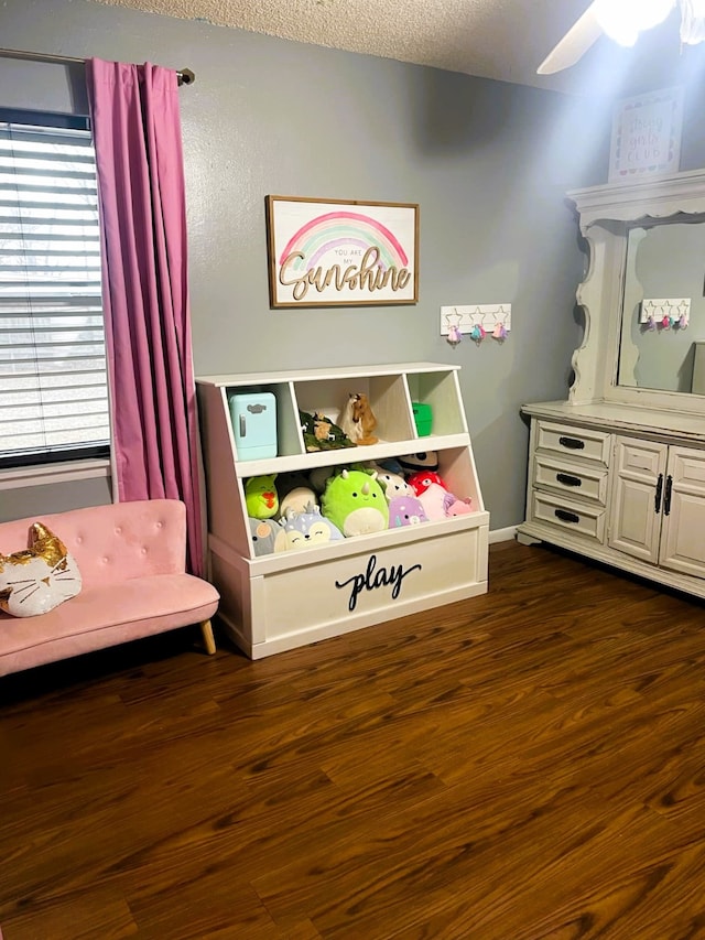 game room with a ceiling fan, dark wood-style flooring, a textured ceiling, and baseboards