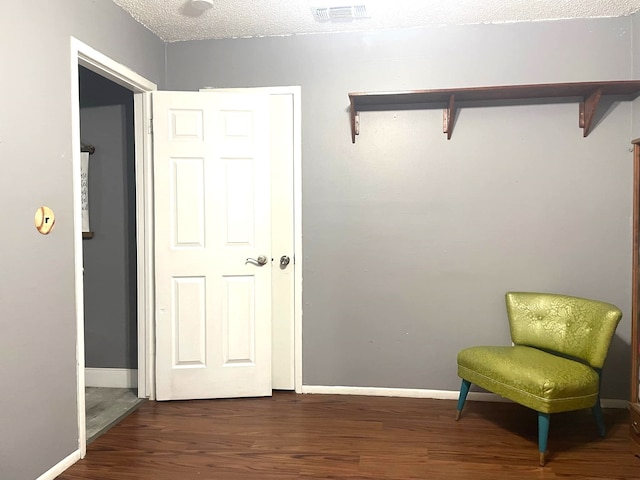 living area with dark wood-style floors, a textured ceiling, visible vents, and baseboards