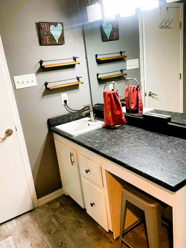 bathroom with a textured wall, vanity, and baseboards