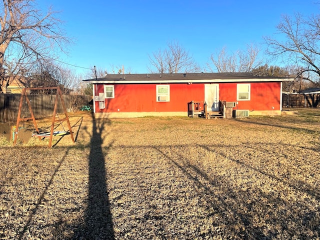 rear view of property with central AC unit, fence, and a yard