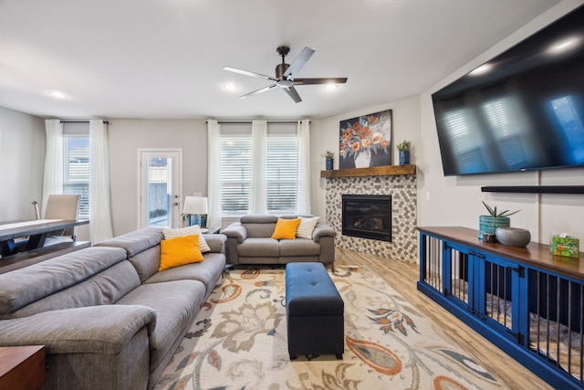 living room with light wood-type flooring, a glass covered fireplace, plenty of natural light, and recessed lighting