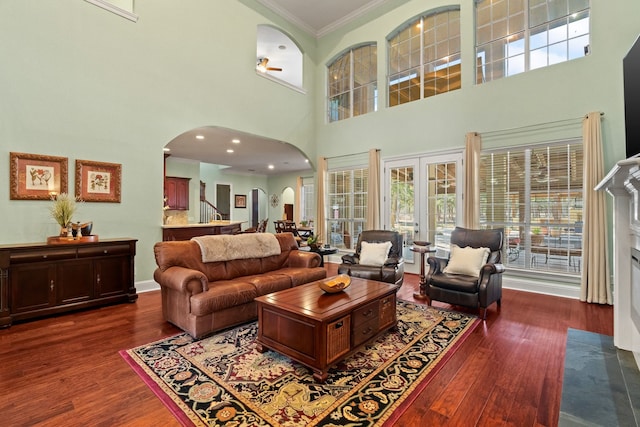 living area with crown molding, arched walkways, dark wood-type flooring, and french doors