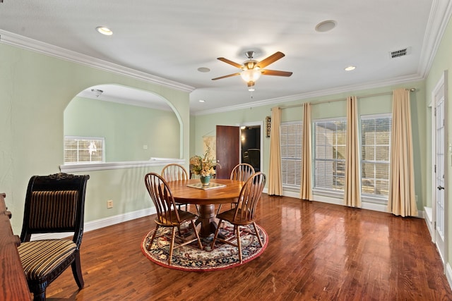 dining area with arched walkways, visible vents, baseboards, dark wood finished floors, and crown molding