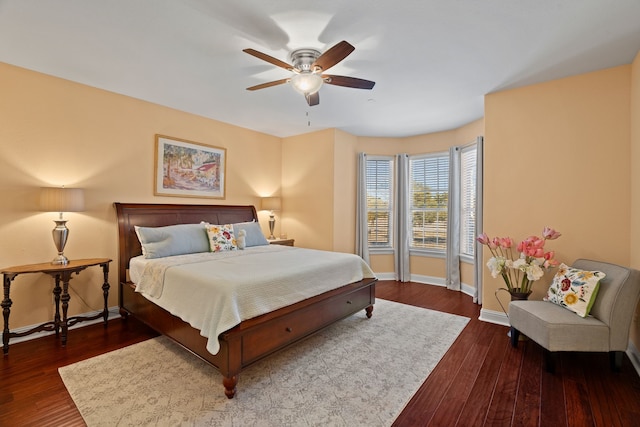 bedroom with dark wood finished floors, a ceiling fan, and baseboards