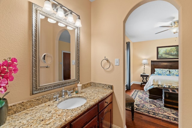 bathroom with baseboards, ceiling fan, wood finished floors, ensuite bathroom, and vanity