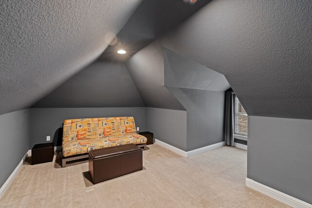 home theater room featuring carpet floors, vaulted ceiling, a textured ceiling, and baseboards