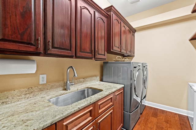 laundry room with cabinet space, baseboards, washer and clothes dryer, dark wood-style floors, and a sink