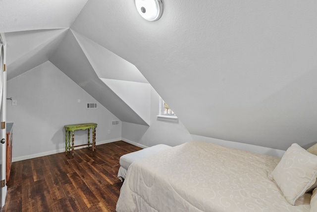 bedroom with lofted ceiling, dark wood-style flooring, visible vents, and baseboards