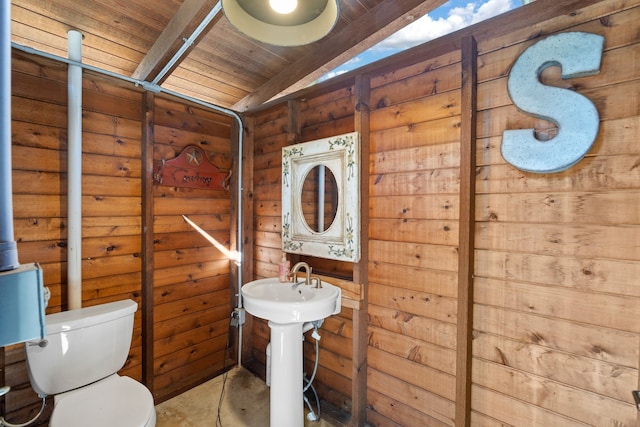 half bath featuring vaulted ceiling, wooden ceiling, a sink, and toilet