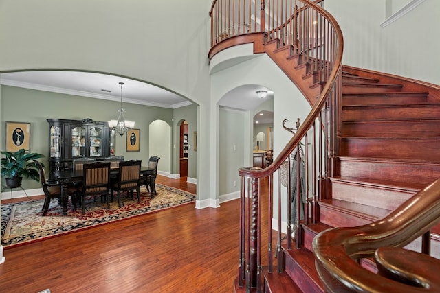 stairway with baseboards, ornamental molding, wood finished floors, and a notable chandelier