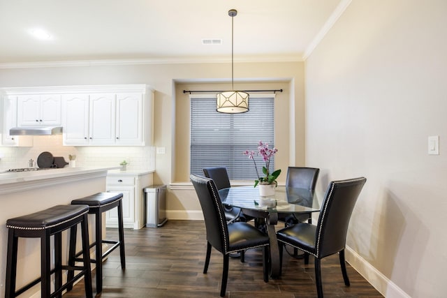 dining area with visible vents, baseboards, dark wood finished floors, and crown molding