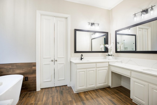 bathroom with double vanity, a closet, a soaking tub, wood finish floors, and a sink