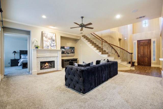 carpeted living room with a premium fireplace, stairway, crown molding, and recessed lighting