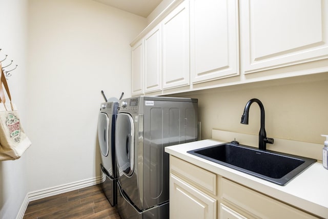 washroom featuring cabinet space, baseboards, dark wood-style floors, separate washer and dryer, and a sink