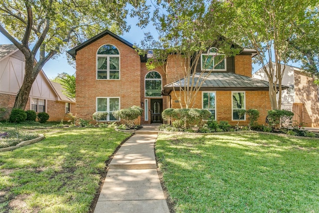 view of front of property featuring brick siding, a front yard, and a standing seam roof